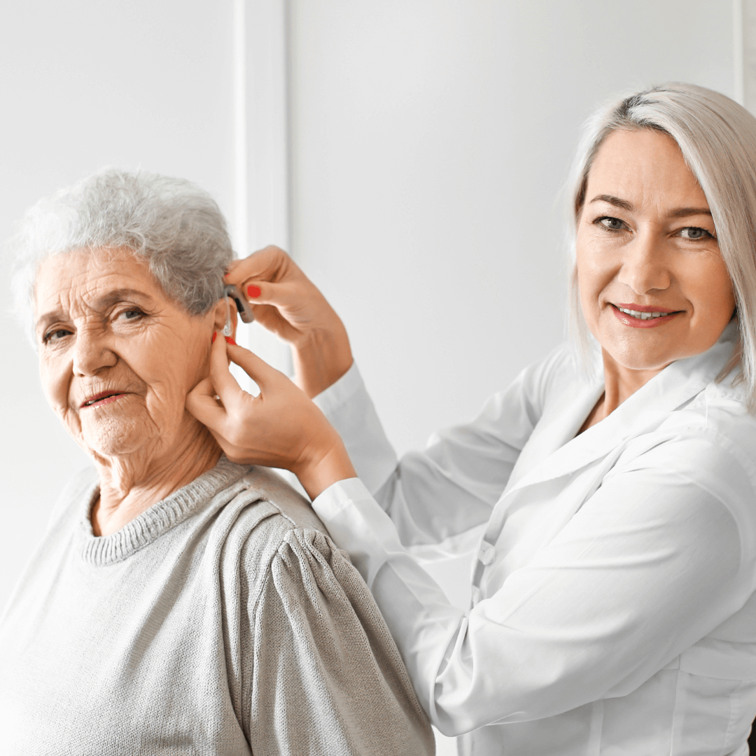 A senior woman smiling while wearing a hearing aid.